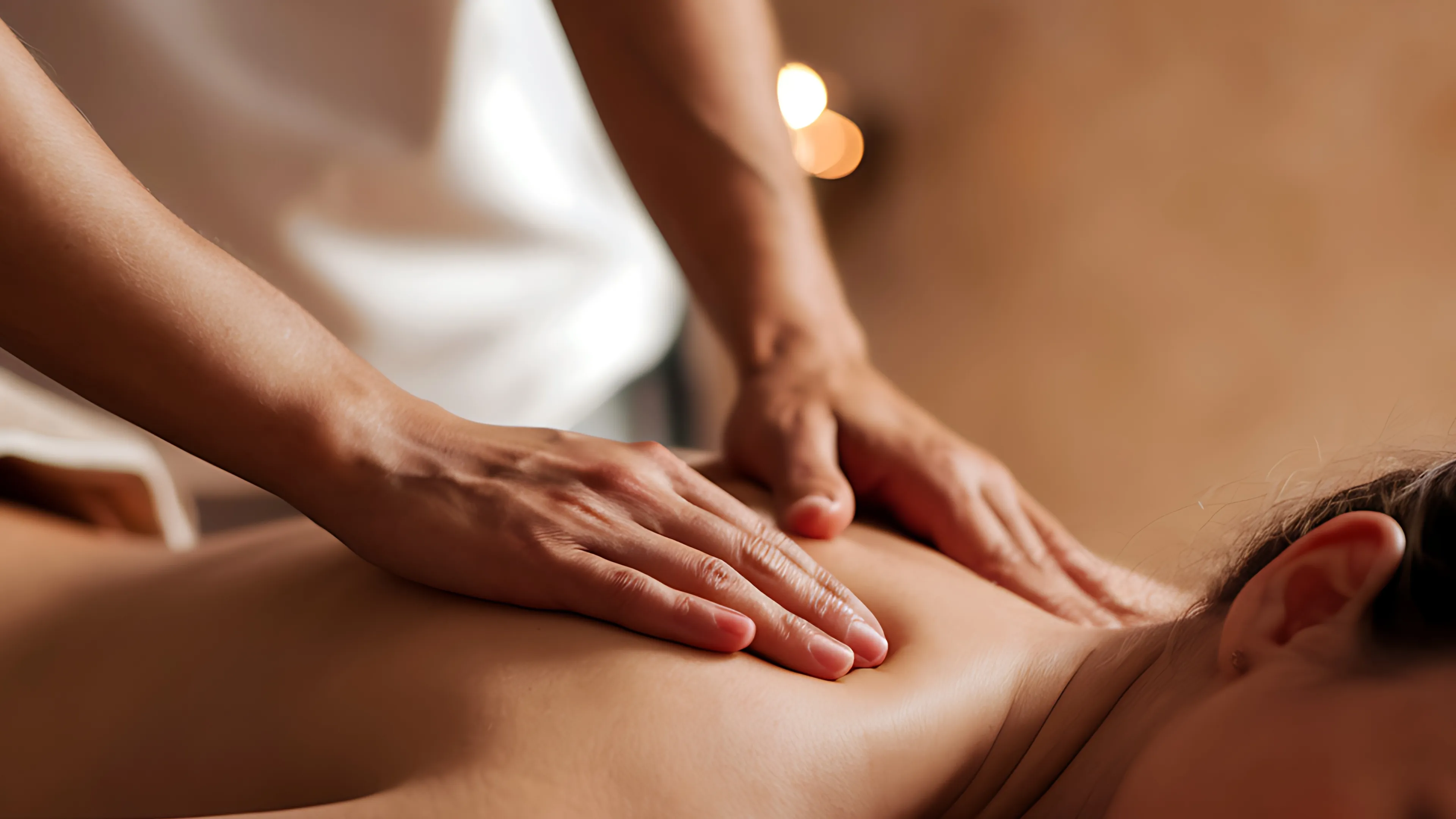 Zwei Hände massieren den Rücken und Schulterbereich eines Menschen