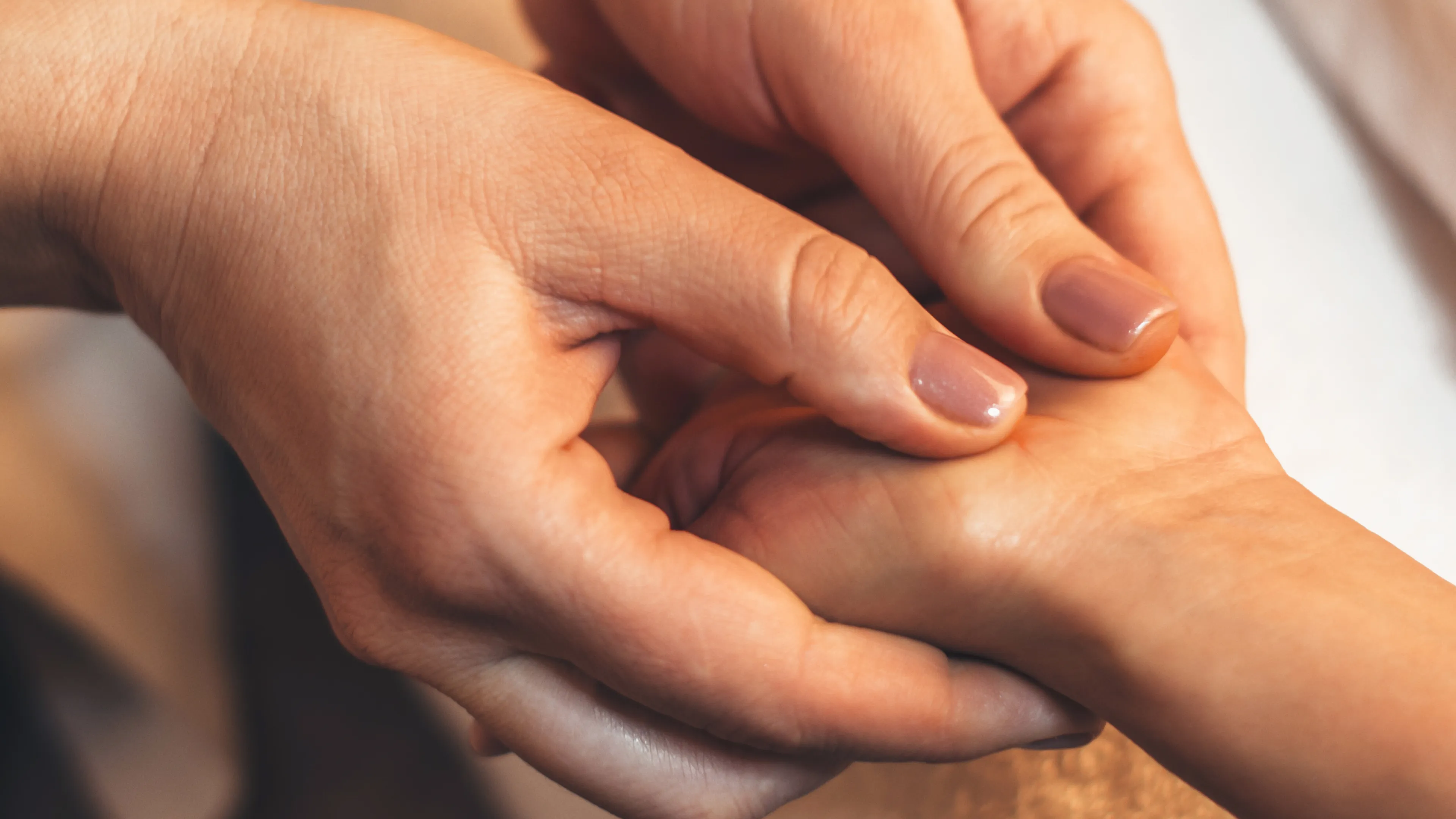 Zwei Daumen massieren den Handballen eines Menschen